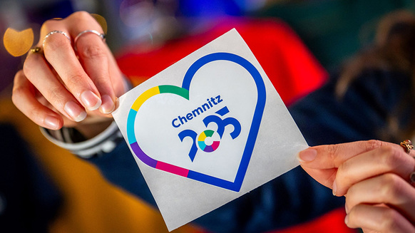 Hände halten Aufkleber mit Logo der Europäischen Kulturregion Chemnitz 2025 | Quelle: © Chemnitz 2025 gGmbH